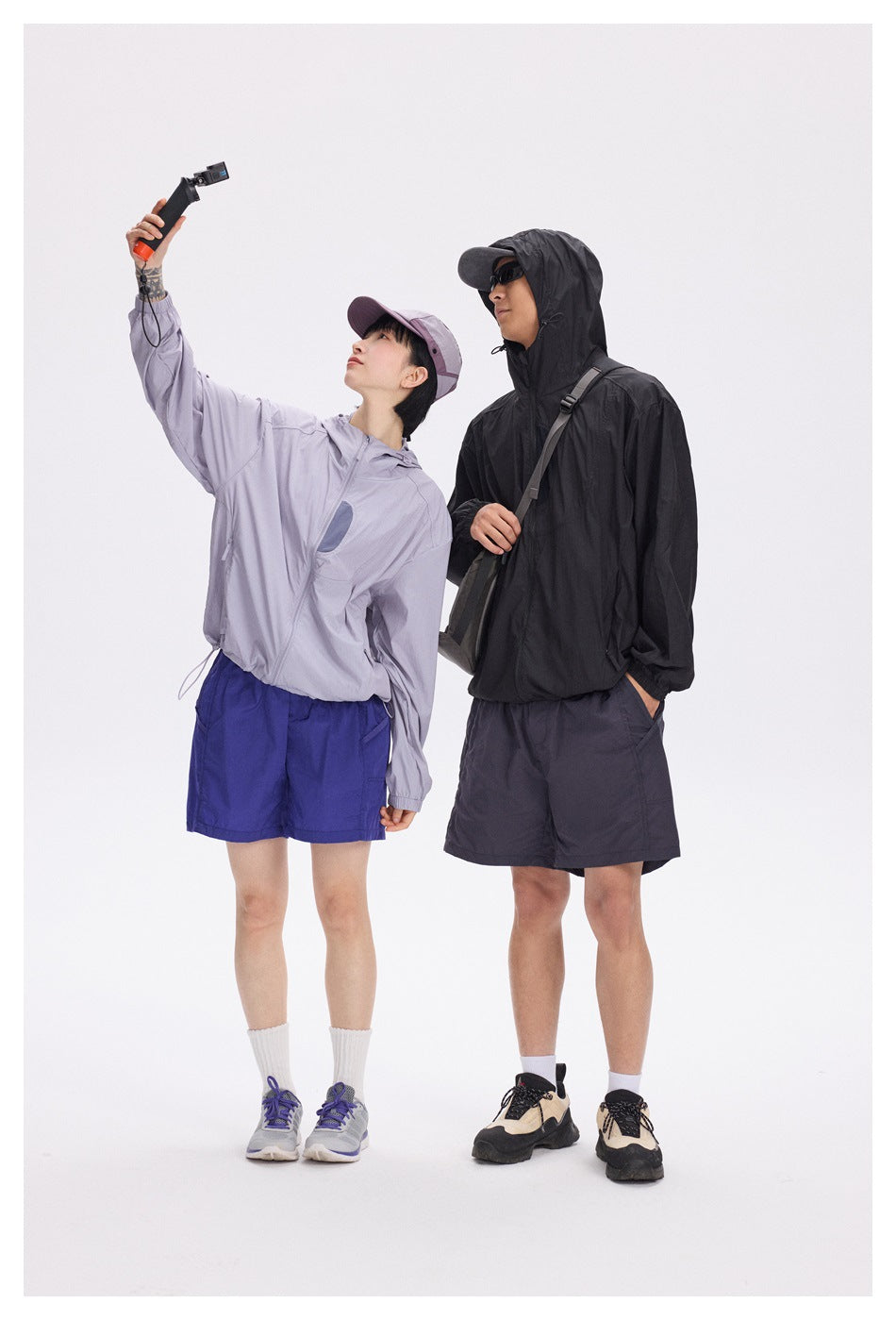 Two models wearing hooded zip jackets in black and pale lavender.