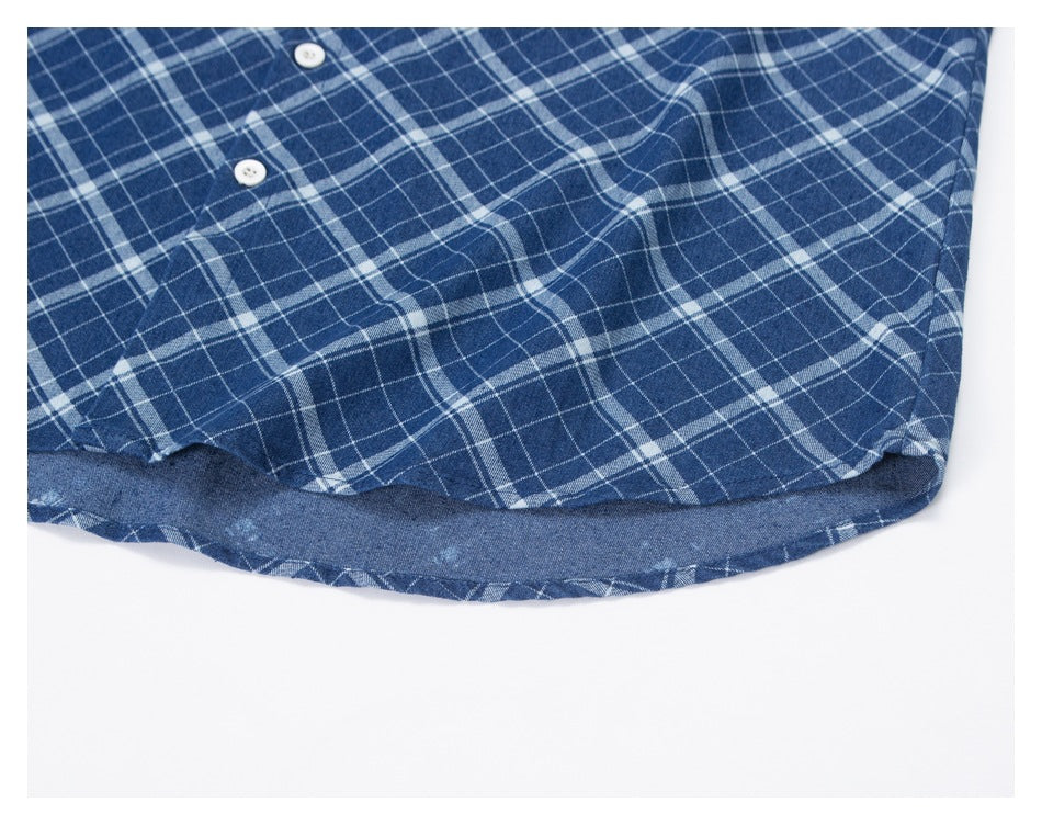Close-up of the curved hem and plaid fabric of a blue-and-white shirt.