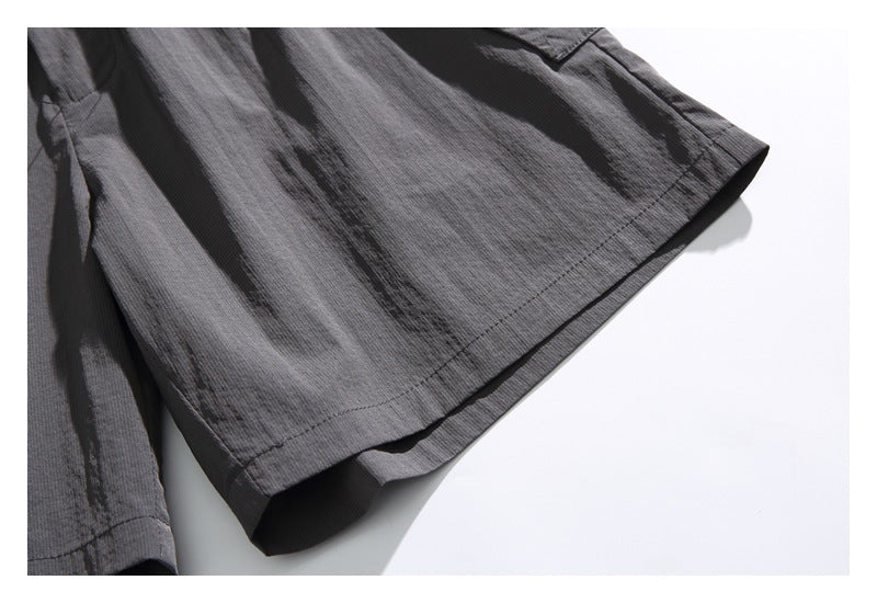 Close-up of the charcoal shorts' stitched hem and textured fabric.