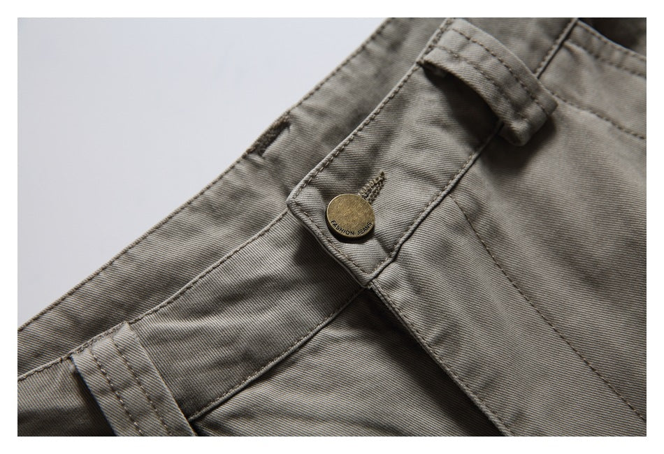 Close-up of gray-olive pants waistband with belt loops and a brass-tone button.