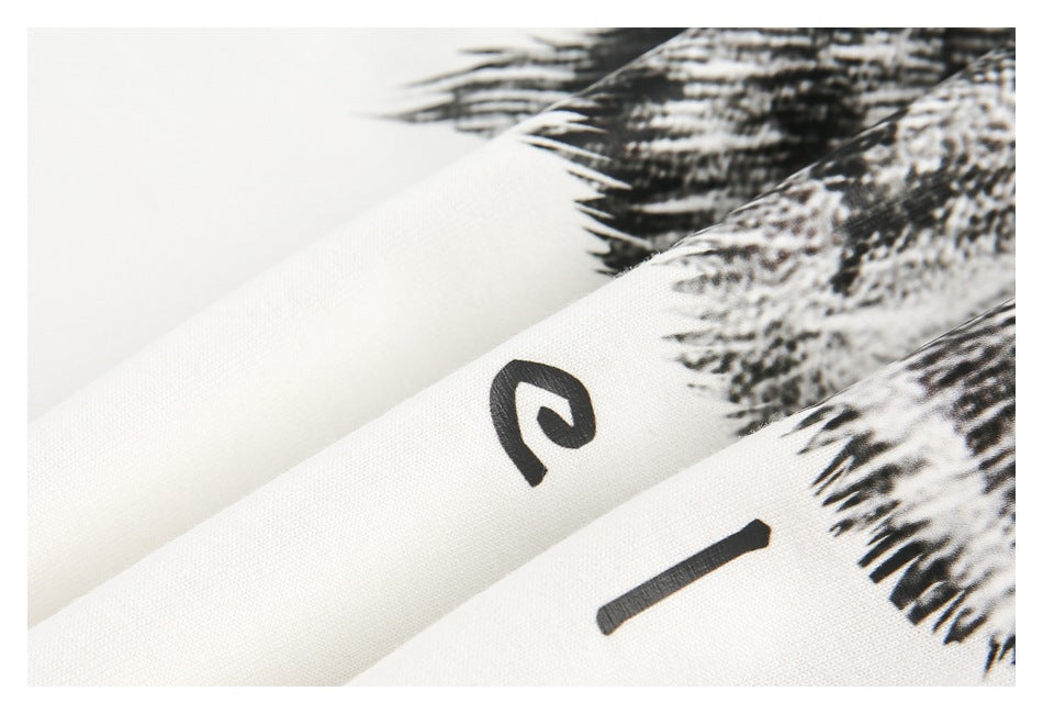 Close-up of folded white fabric showing part of the black cat print and stylized lettering.