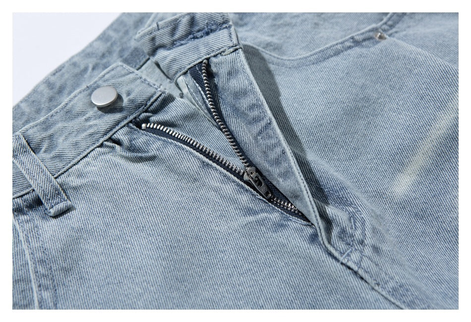 Close-up of the open zipper fly and button on light-wash jeans.