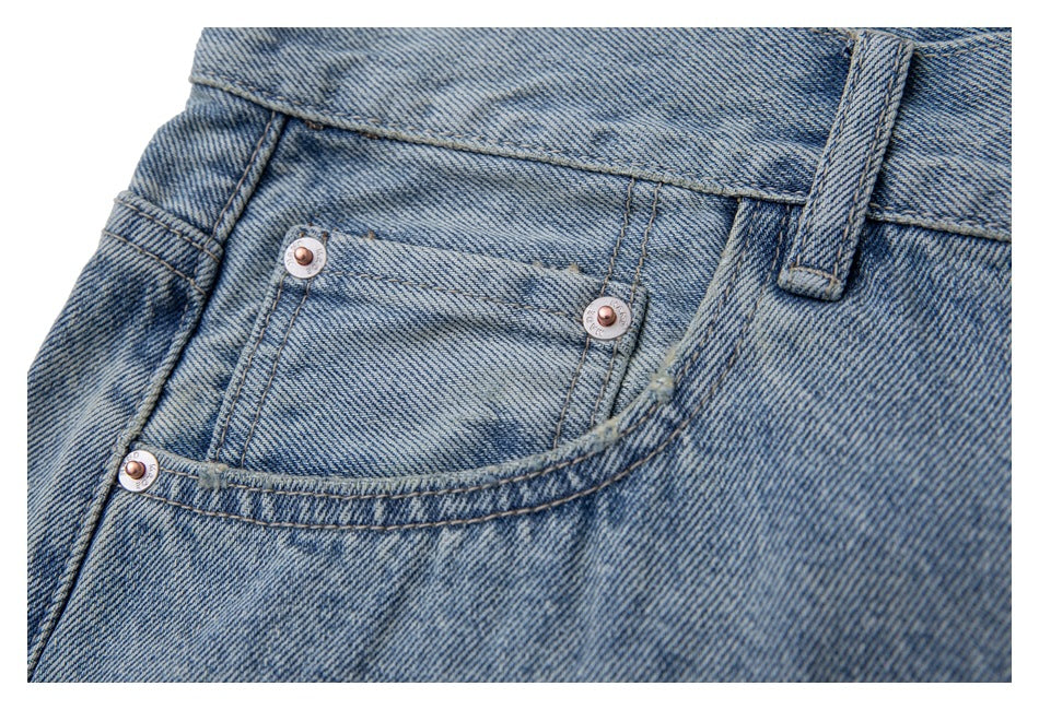 Close-up of the front coin pocket and metal rivets on light blue washed jeans.