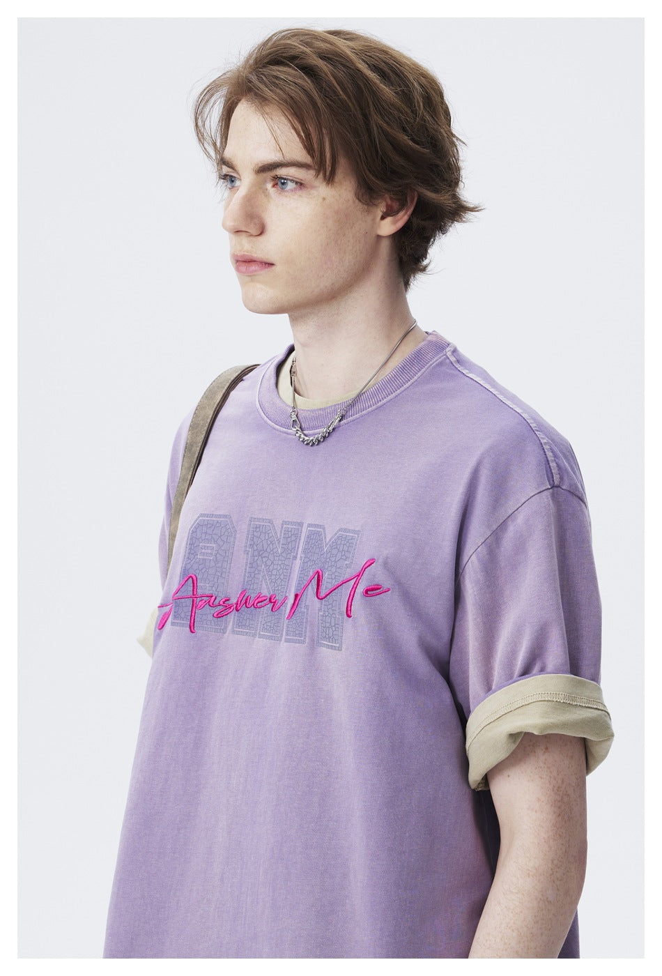 Close view of a model wearing a lavender T-shirt with beige rolled cuffs and a pink-and-gray chest graphic.