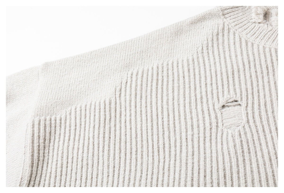 Close-up of an ivory rib-knit garment with a small stitched opening.