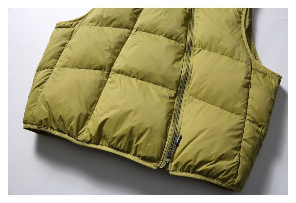 Close-up of the olive-green vest's lower front, quilted panels, zipper pull, and hem.