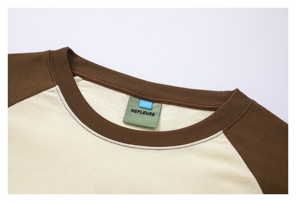 Close-up of the cream and brown raglan T-shirt neckline, ribbed collar, and XL brand label.