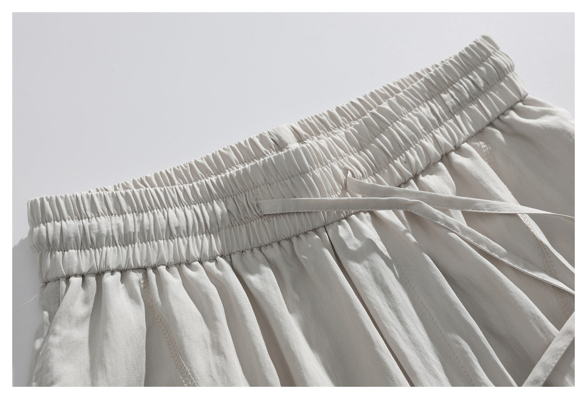 Close-up of cream bottoms with a gathered elastic waistband and matching drawstrings.