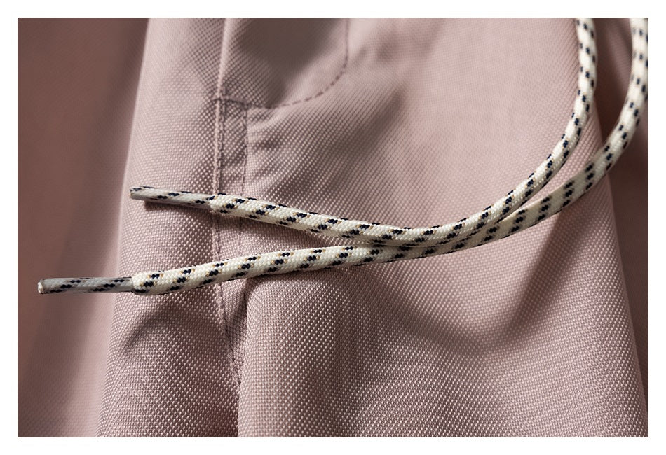 Close-up of patterned cream drawstrings crossing over the textured mauve fabric and a seam.