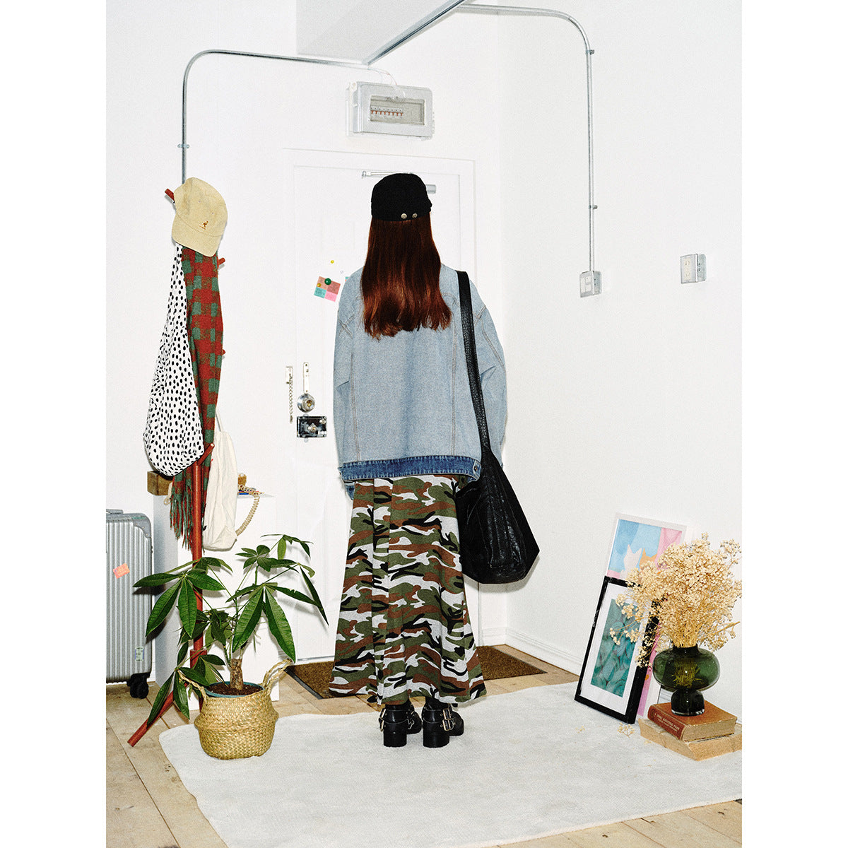 Back view of a model in a light-wash denim jacket and long camouflage skirt.