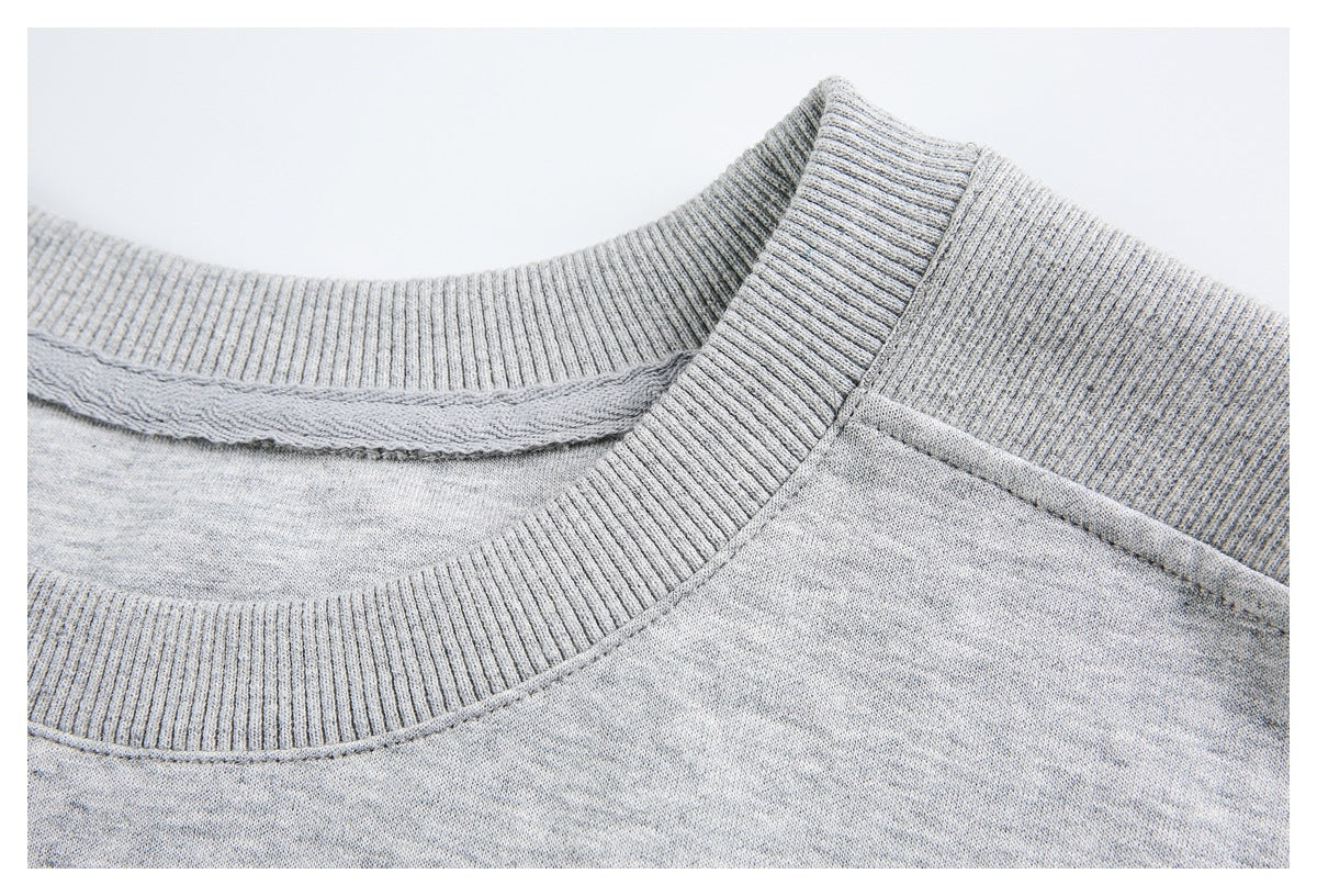 Close-up of a light heather-gray shirt's ribbed collar, shoulder seam, and neckline stitching.