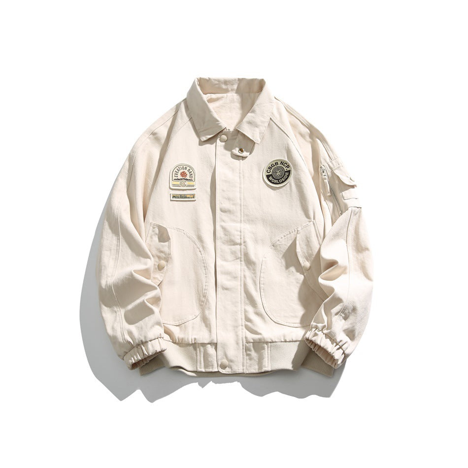 Front view of a cream jacket with decorative chest patches, large pockets, a high collar and elastic cuffs.