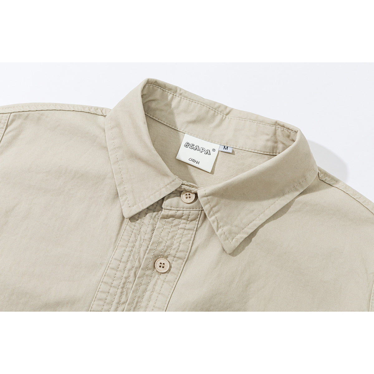 Close-up of a light beige short-sleeve shirt collar, buttons, and stitched placket.