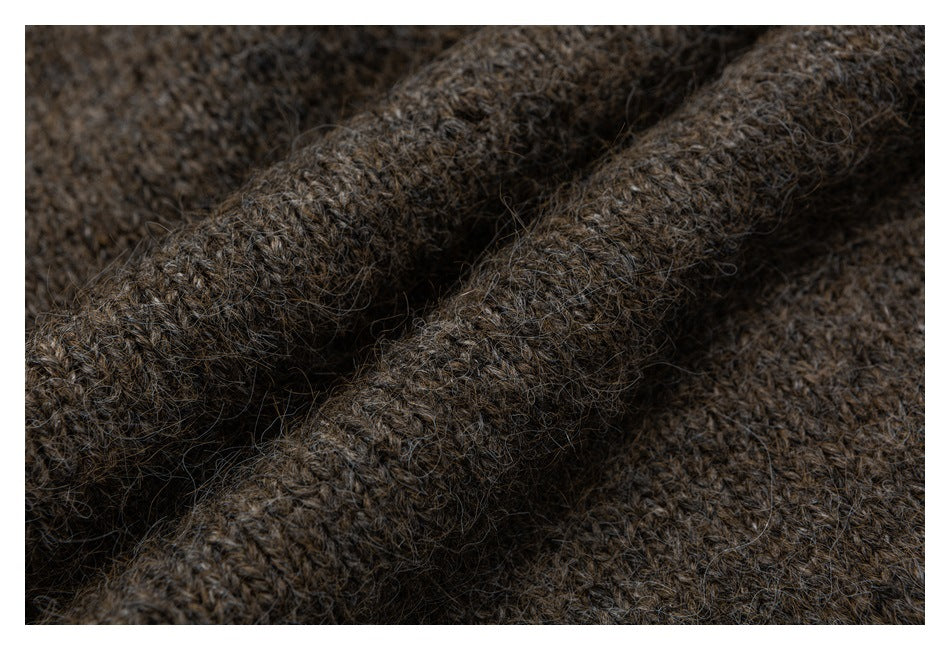 Close-up of dark brown fuzzy knit fabric gathered into folds, showing its textured stitches.