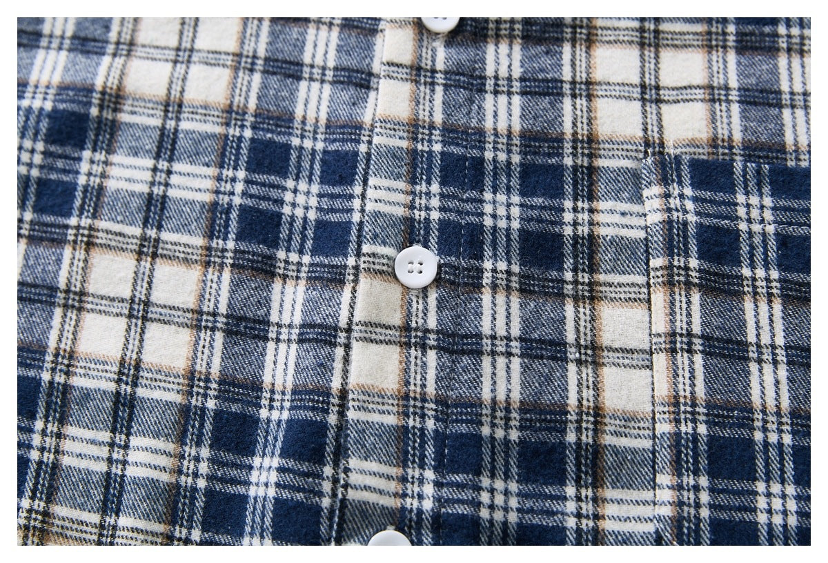 Close-up of a navy, cream, gray, and tan plaid shirt placket with white buttons.