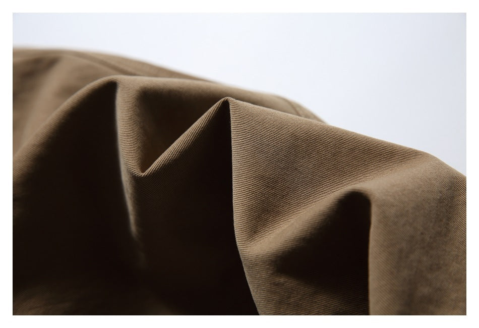 Close-up of brown fabric draped into folds, showing its fine diagonal weave.