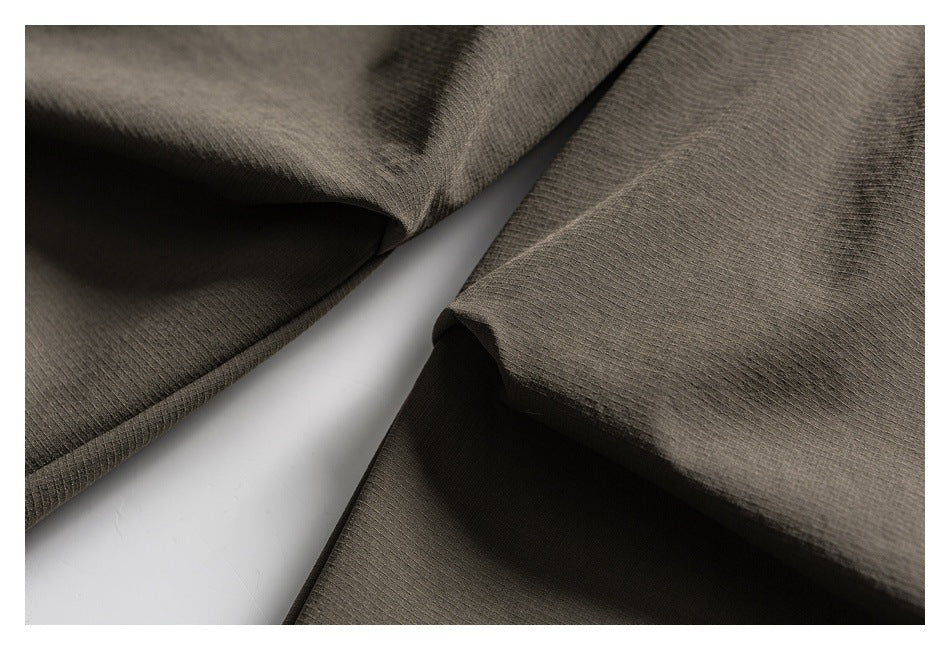 Close-up of olive-gray garment panels and folded edges, showing stitching and fabric texture.
