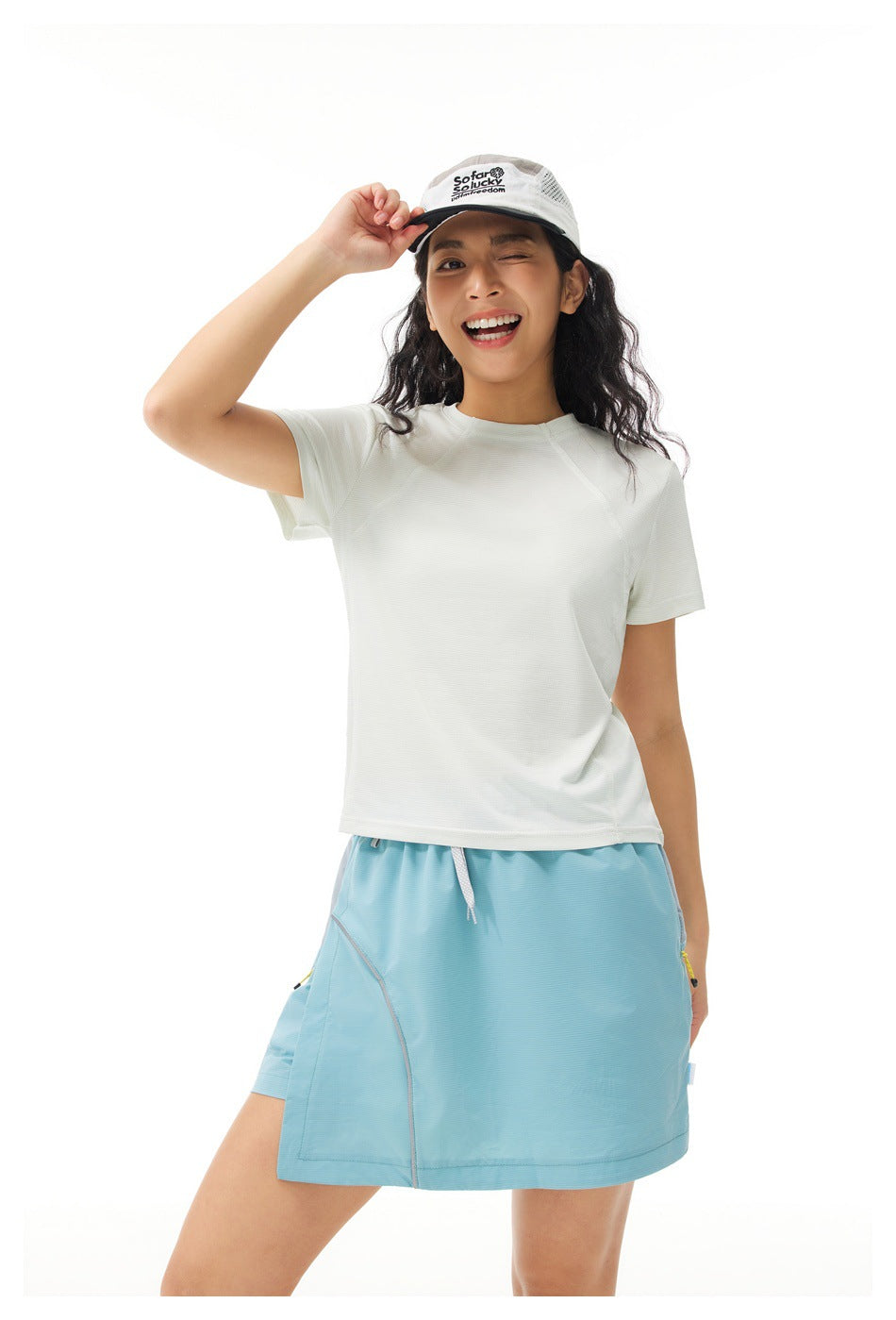 Model wearing an off-white raglan-seam shirt and light blue athletic skirt, shown from the front.