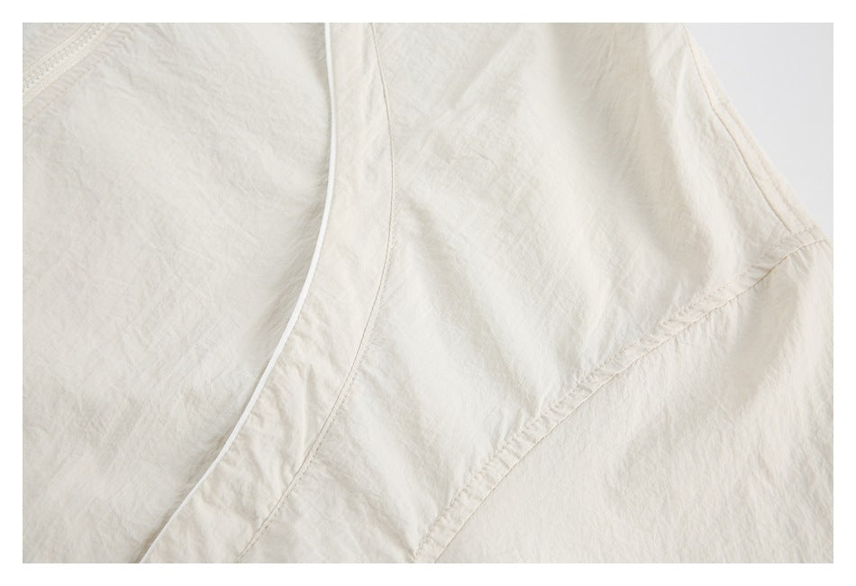 Close-up of cream jacket fabric, curved seam, and narrow white piping.