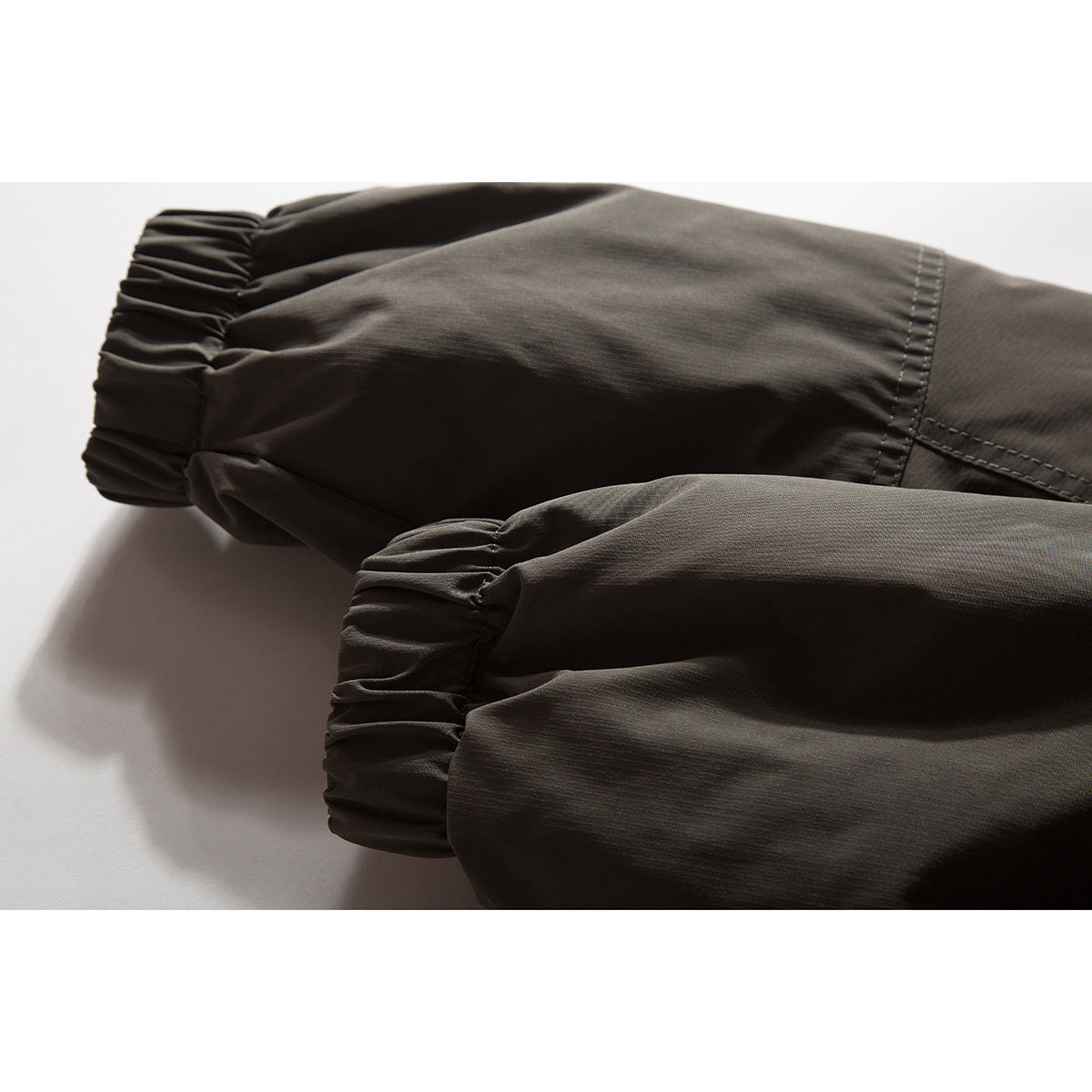 Close-up of the jacket's sleeves and gathered elastic cuffs in charcoal brown.