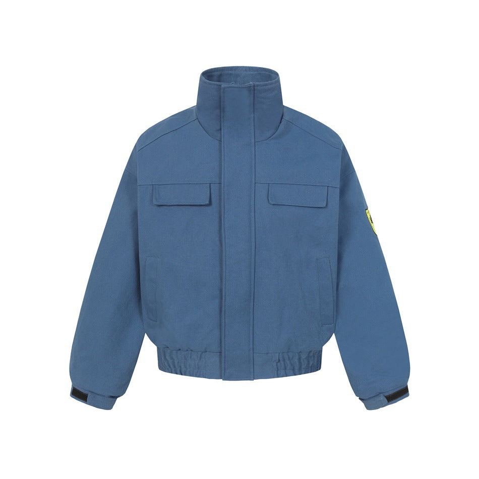 Blue stand-collar bomber jacket, front view, with chest flap pockets, elastic hem and yellow sleeve patch