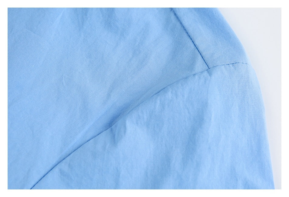 Close-up of light blue garment fabric with a curved stitched seam.
