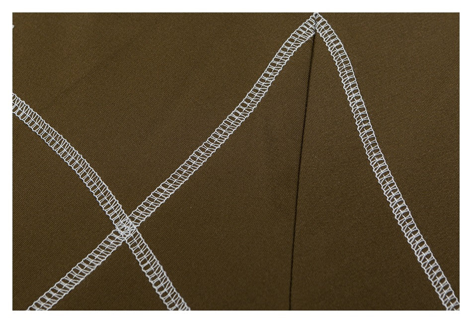 Close-up of olive fabric with intersecting white overlock seams and a vertical folded seam.