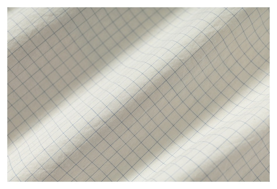 Close-up of off-white fabric with a fine blue grid pattern.