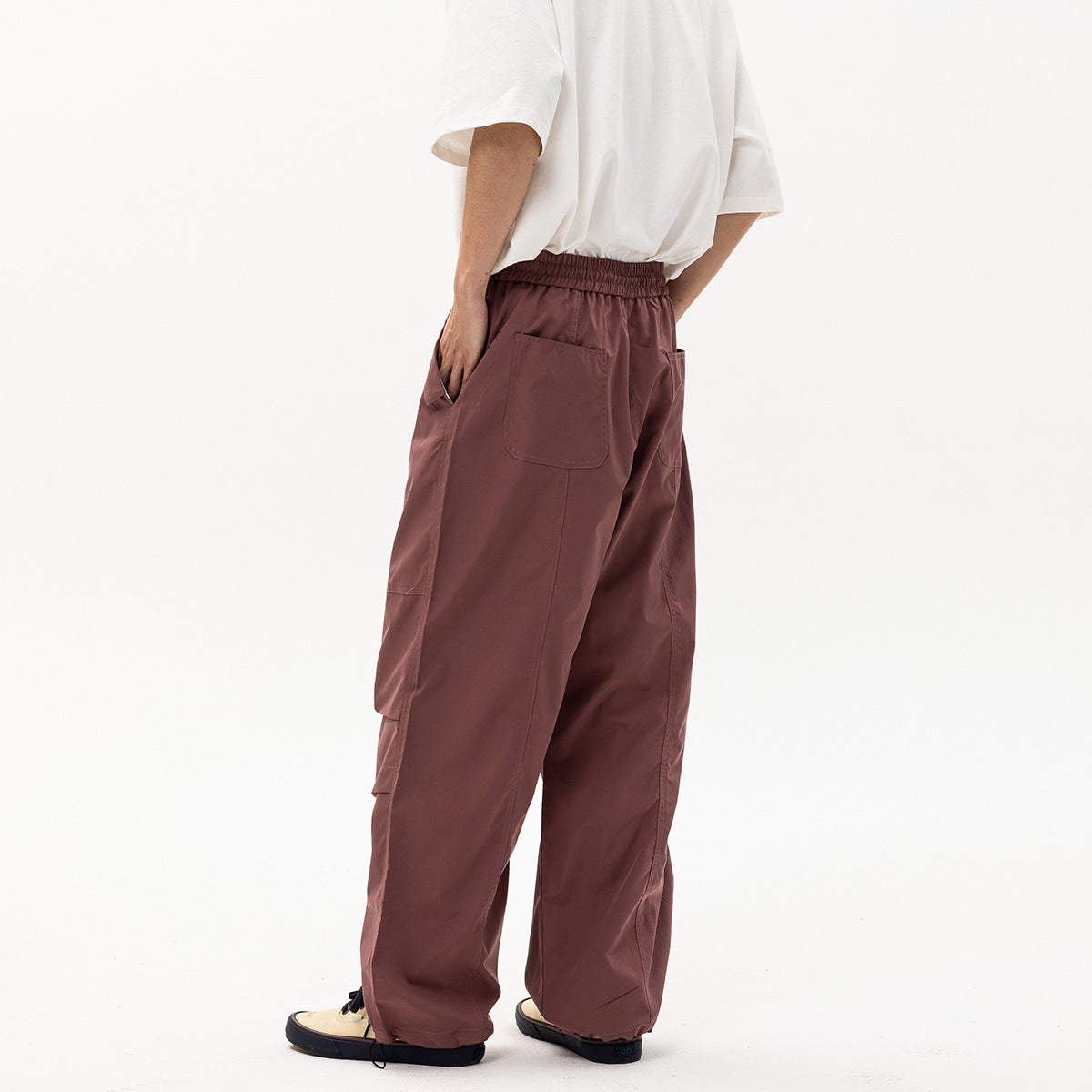 Rear-side view of a model wearing loose mauve cargo pants with an elastic waist and back pockets.