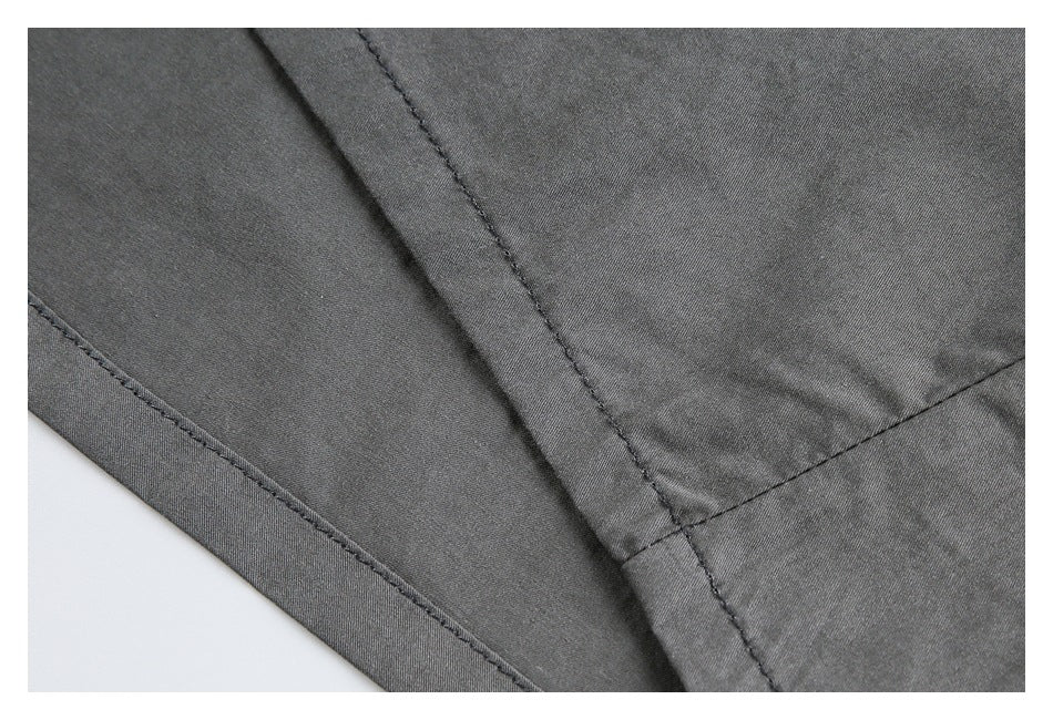 Close-up showing stitched seams and overlapping panels on charcoal gray garment fabric.