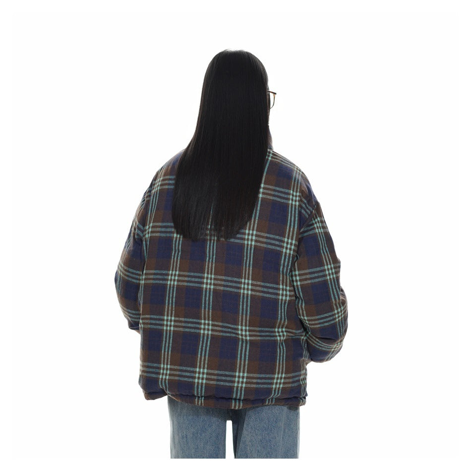 Back view of a model wearing an oversized navy and brown plaid jacket with turquoise stripes.