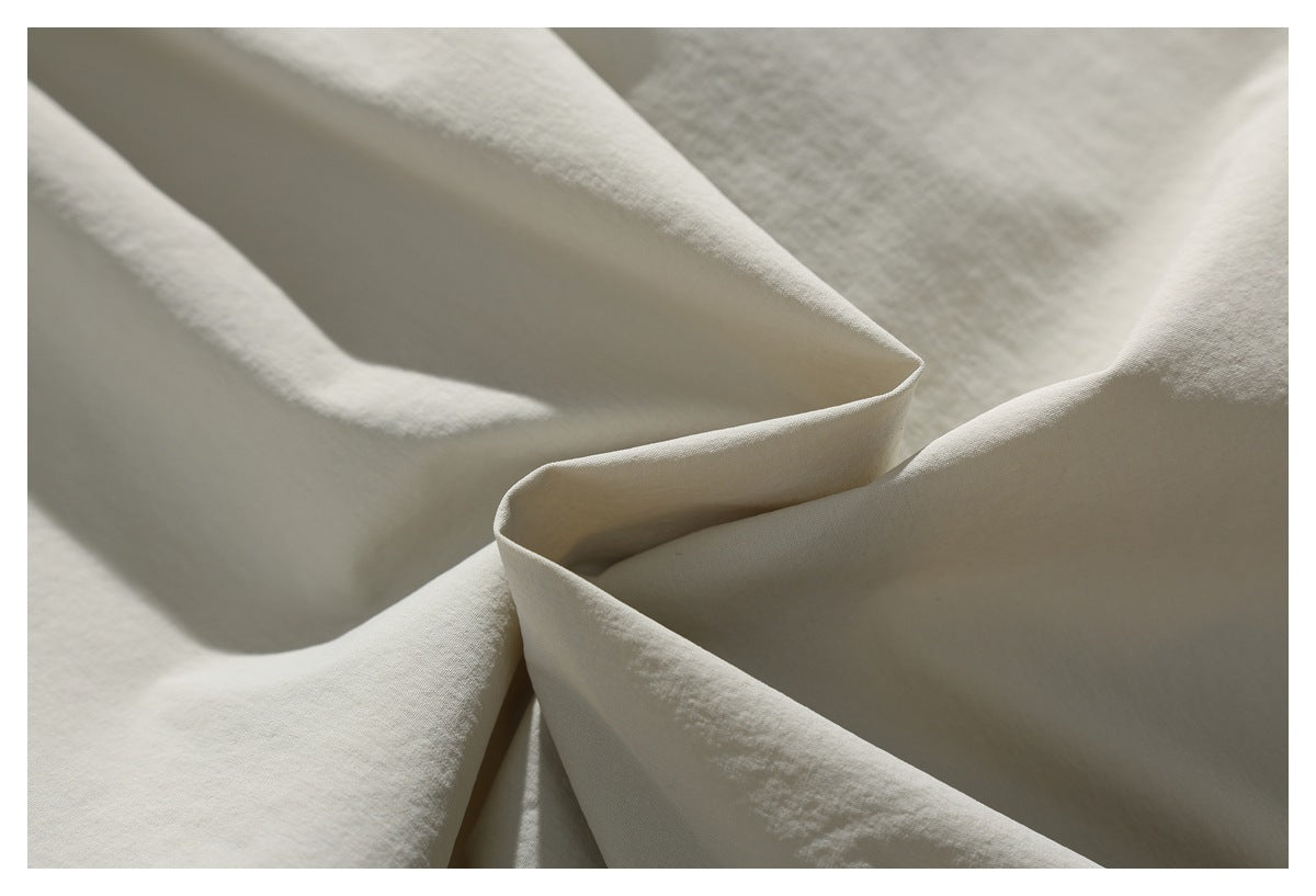 Macro view of light ivory shorts fabric folded to show its surface and drape.
