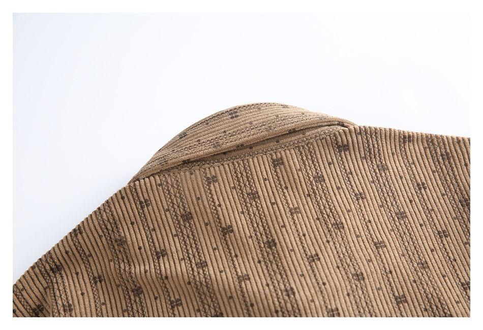 Close-up of brown ribbed fabric with scattered dark motifs and a folded garment edge.