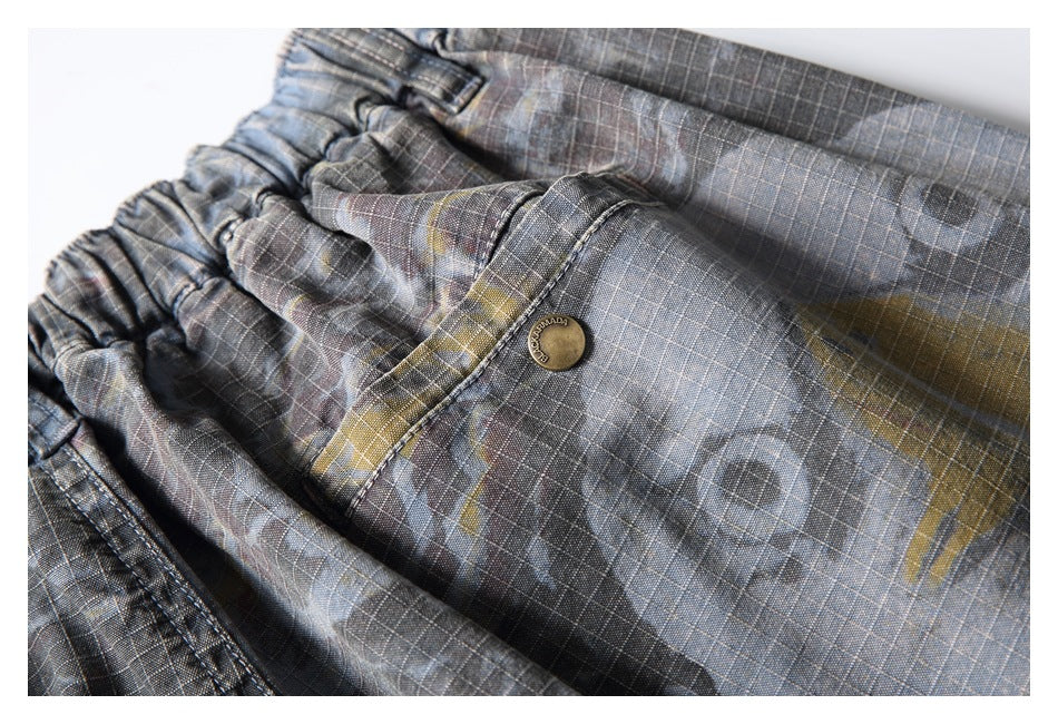 Close-up of gray plaid shorts with a buttoned front pocket and a gathered waistband.