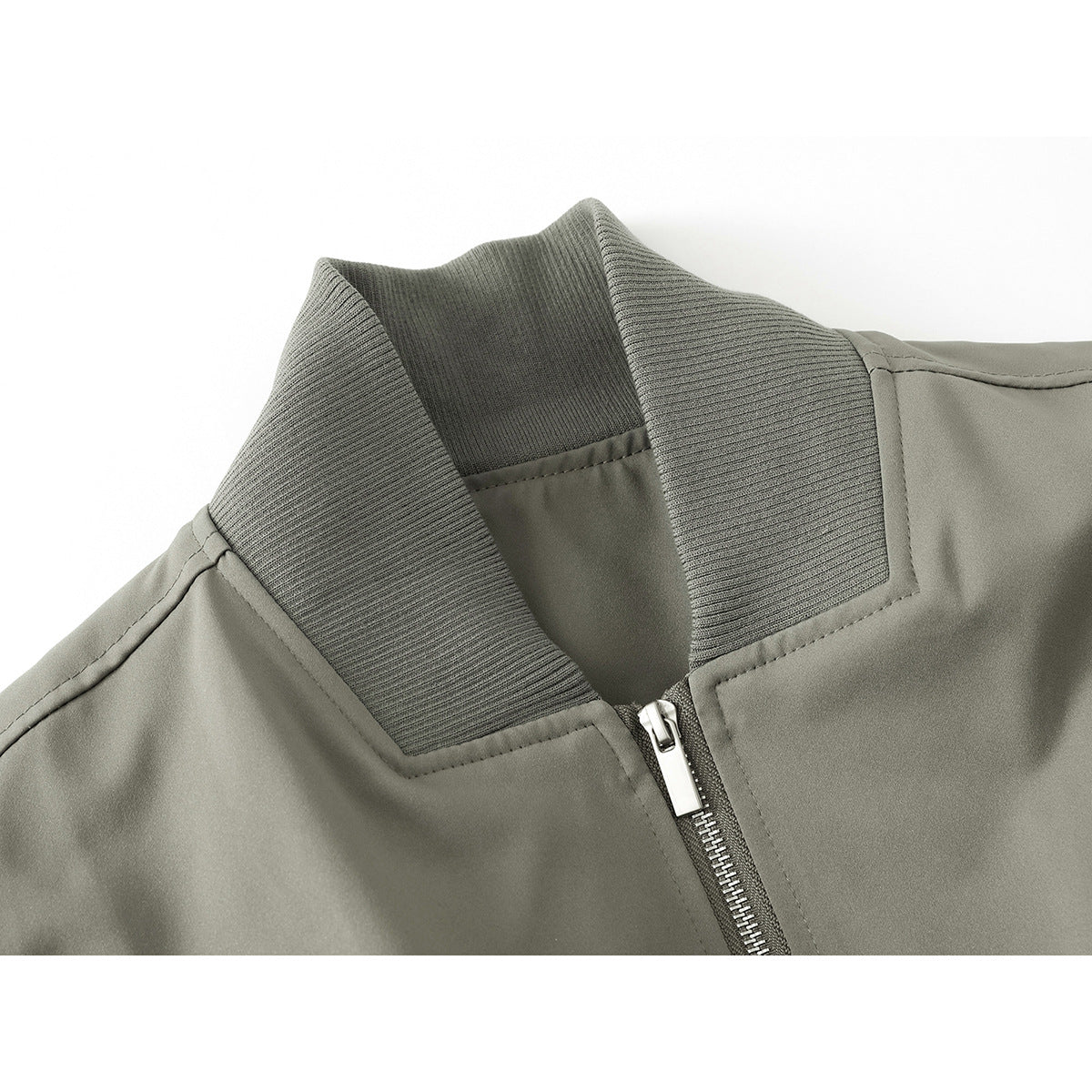 Close-up of an olive-gray jacket's ribbed stand collar, stitching, and silver center zipper.