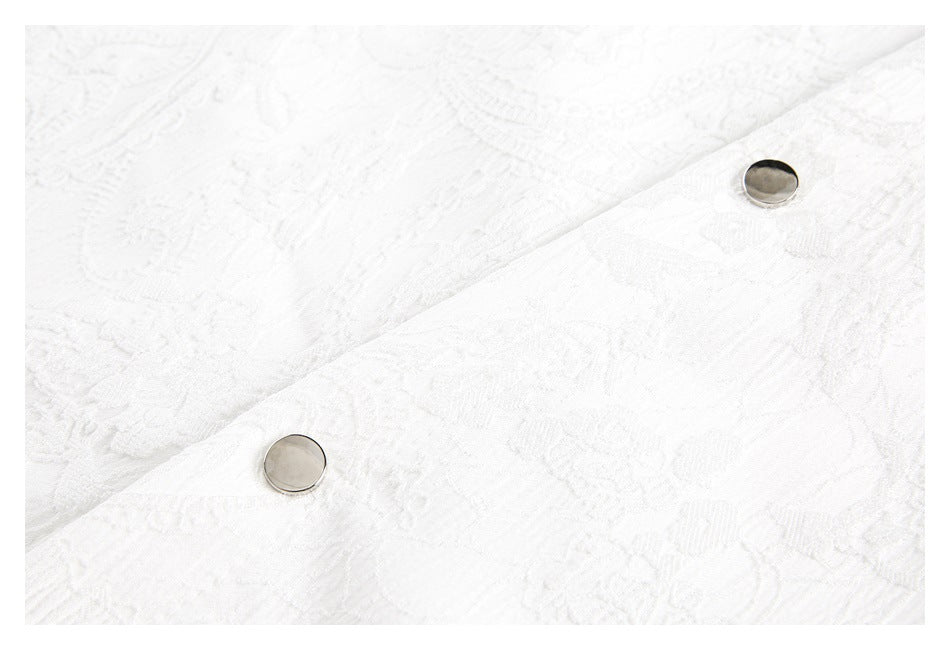 Close-up of two round metal buttons on white fabric with a raised floral and geometric pattern.