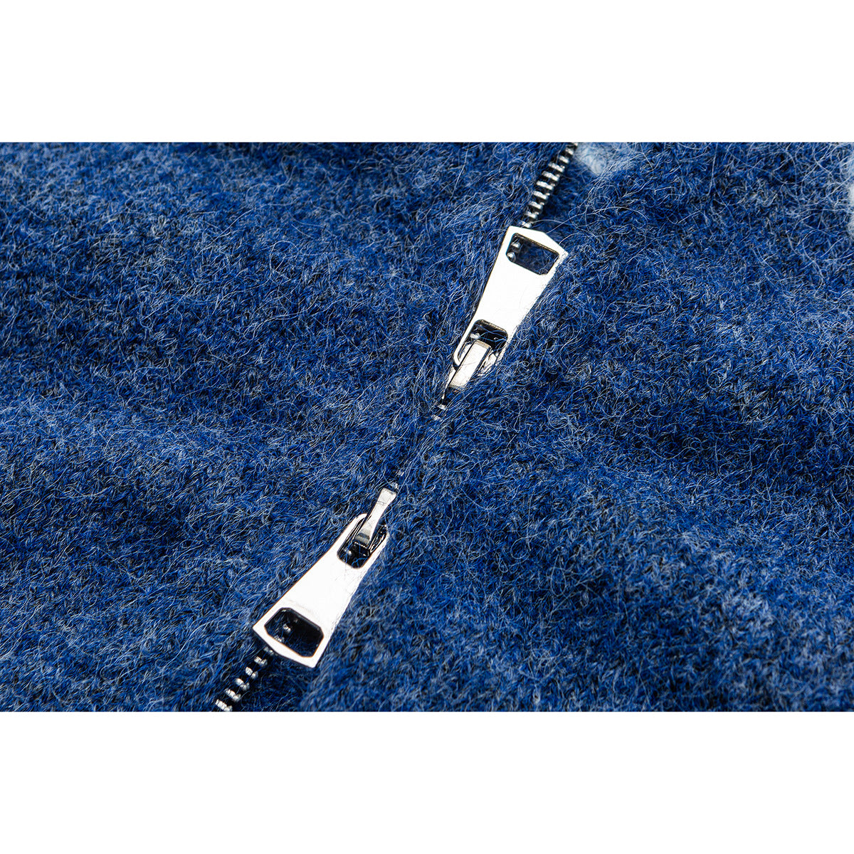 Close-up of two metal zipper pulls on the textured blue knit sweater.