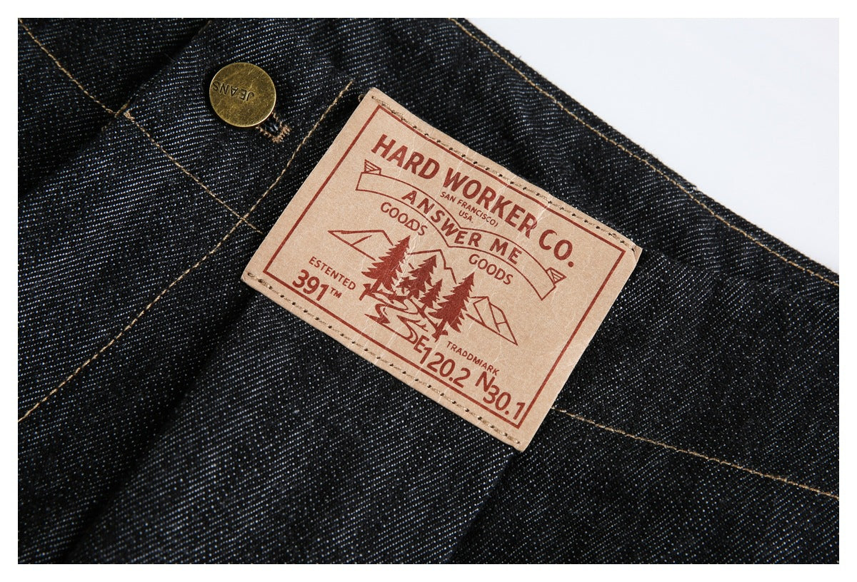 Close-up of a tan branded patch and brass button sewn onto dark indigo jeans.