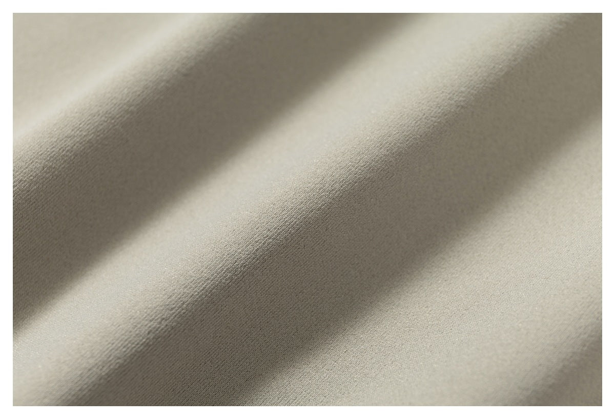 Close-up of smooth taupe-gray fabric with soft folds and diagonal shadows.