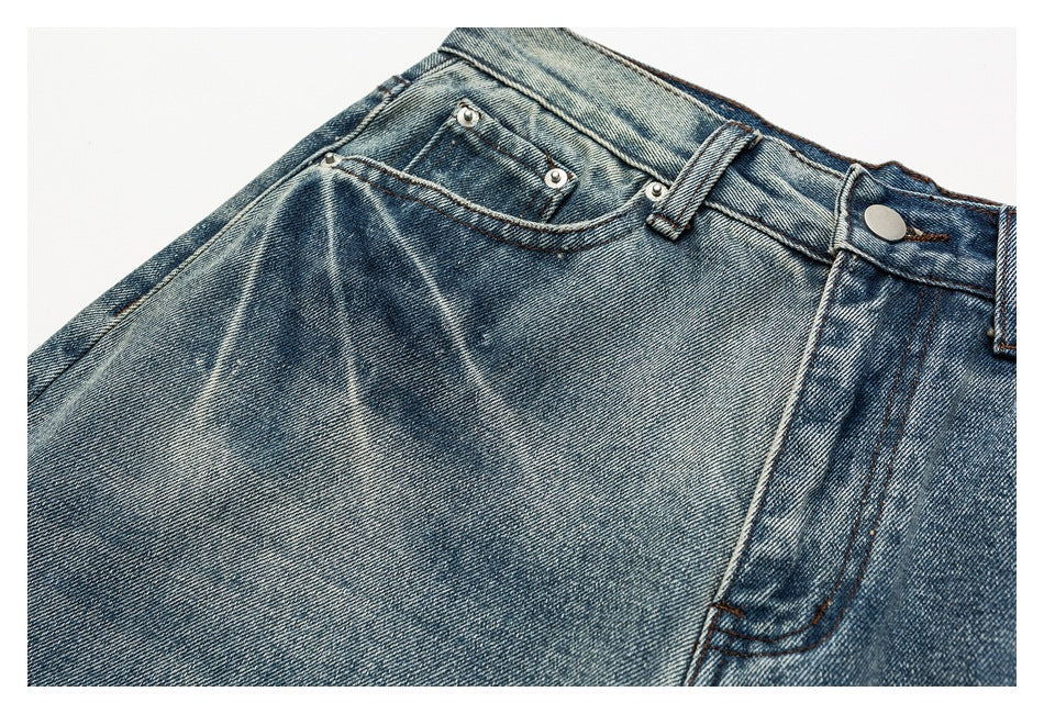 Close-up of faded blue jeans showing the coin pocket, rivets, belt loop and metal button.