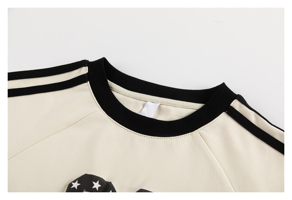 Close-up of the cream tee's black crew neckline, raglan seams, and twin black shoulder stripes.