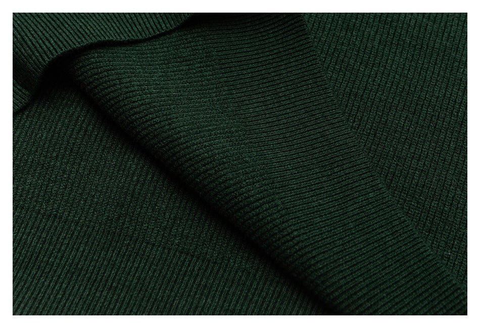 Close-up of dark green rib-knit fabric folds and contrasting knit directions.