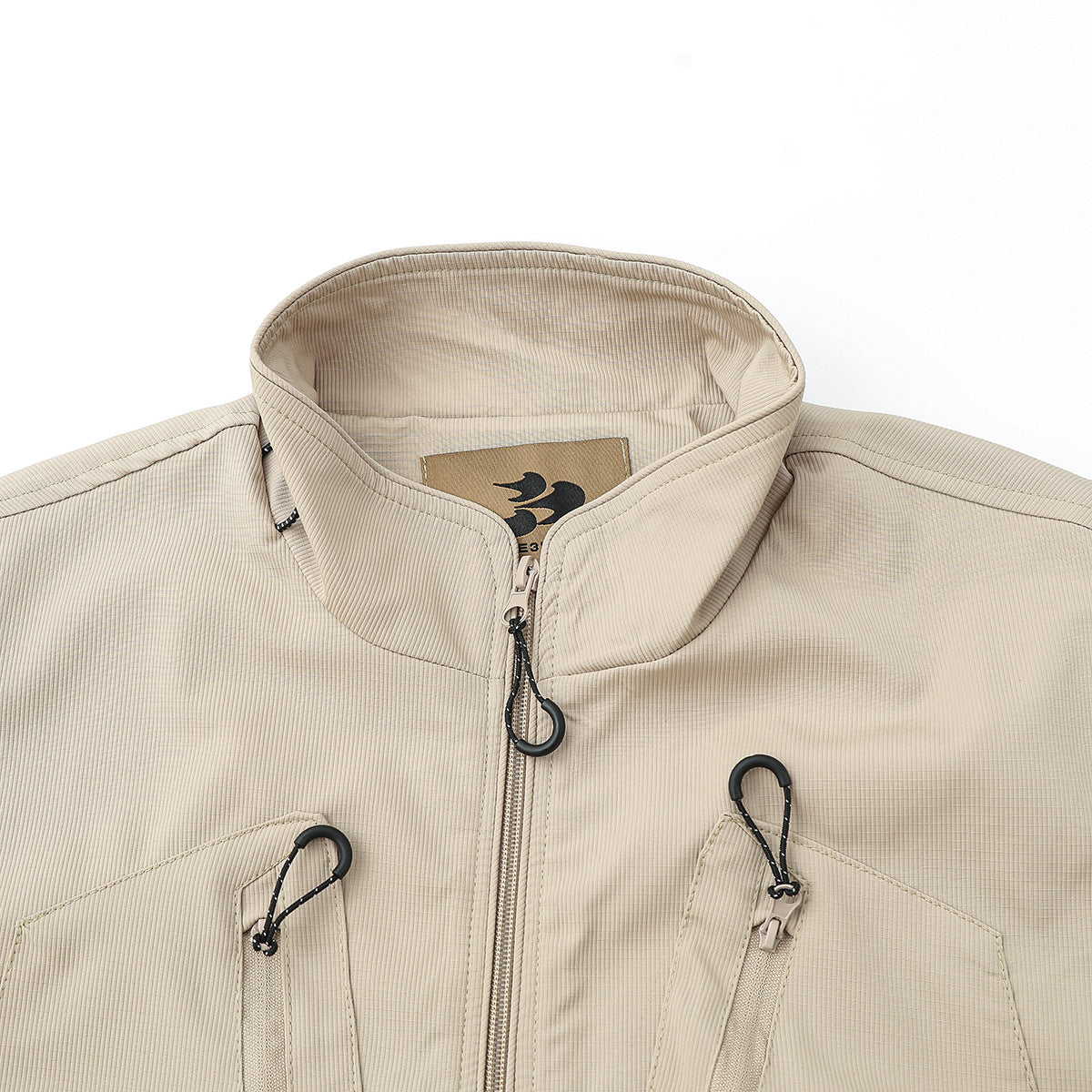 Close-up of a beige vest collar, front zipper, black zipper pull, and upper chest pockets.