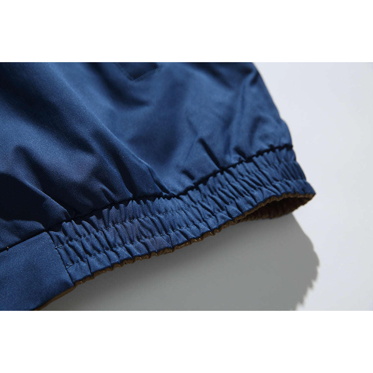 Close-up of the navy jacket’s gathered elastic hem and brown lining edge.