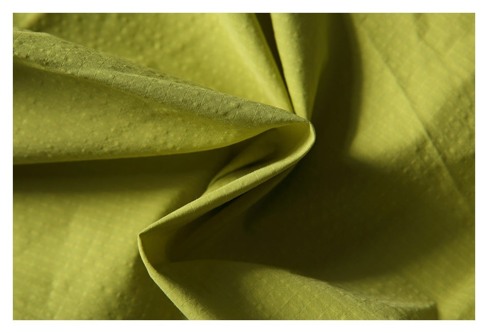Close-up of lime-yellow shorts fabric folded to show its texture and drape.