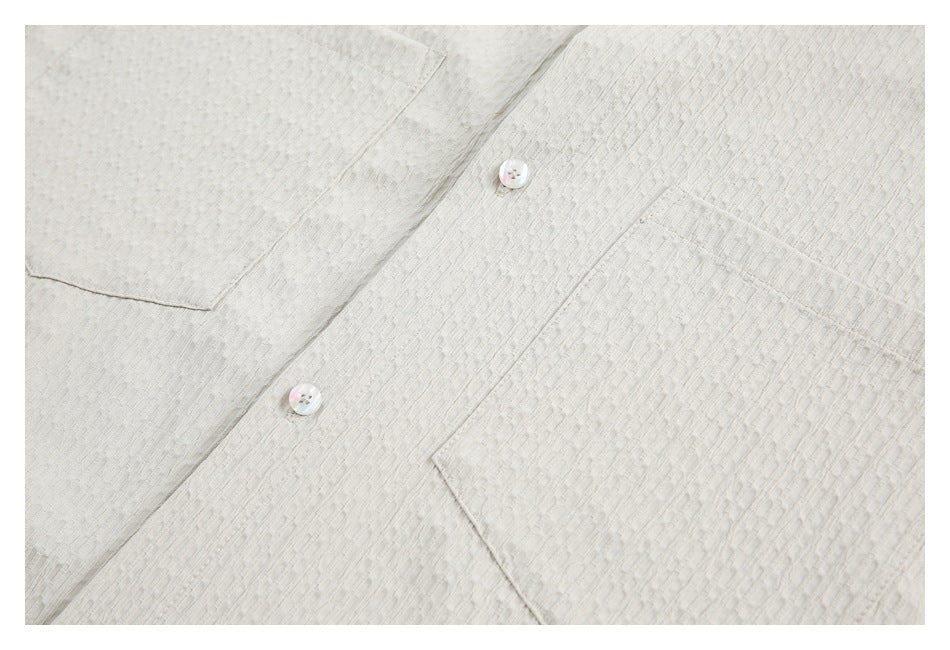 Close-up of an ivory textured shirt front, showing the button placket and chest pockets.