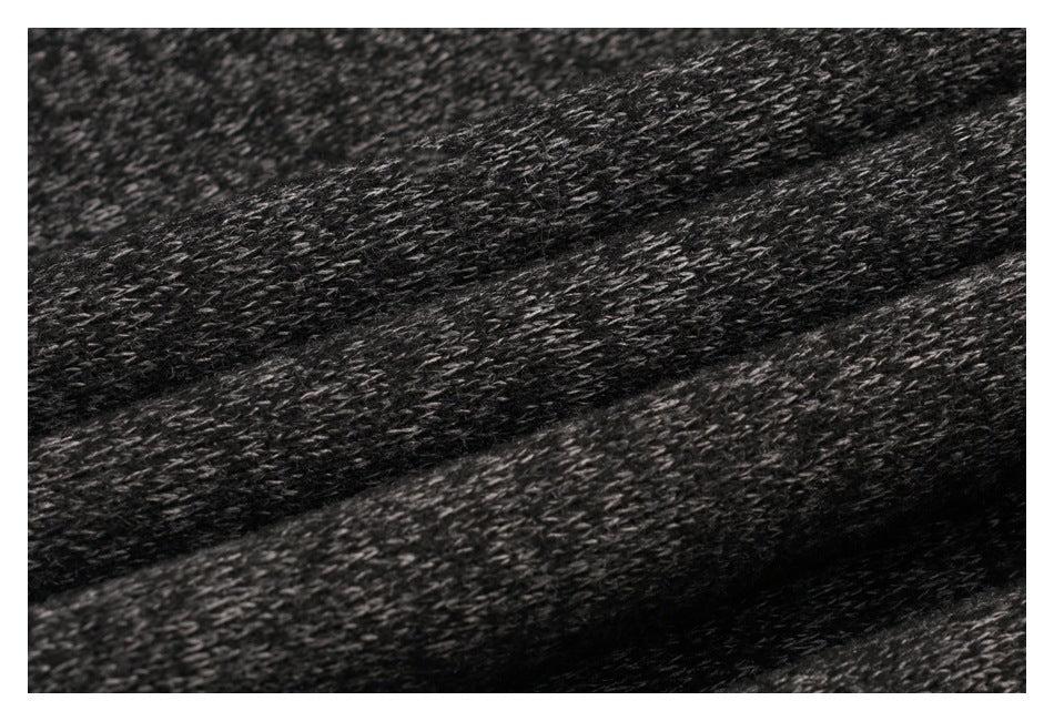 Close-up of dark charcoal knit fabric with mottled gray fibers and visible stitch texture.