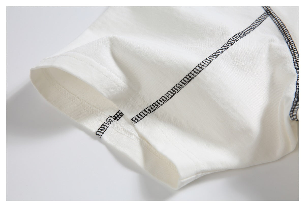 Close-up of the off-white T-shirt sleeve hem and black contrast overlock seam.