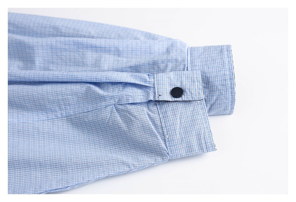 Close-up of a plaid sleeve cuff with a black snap fastener and adjustment tab.