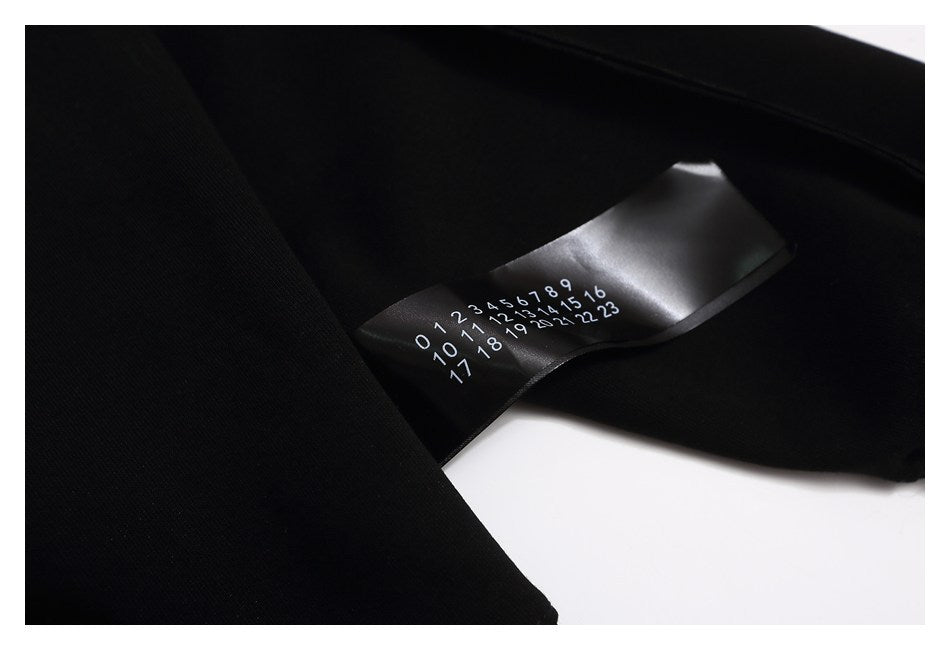 Close-up of a black sweatshirt with a black label printed with rows of white numbers.